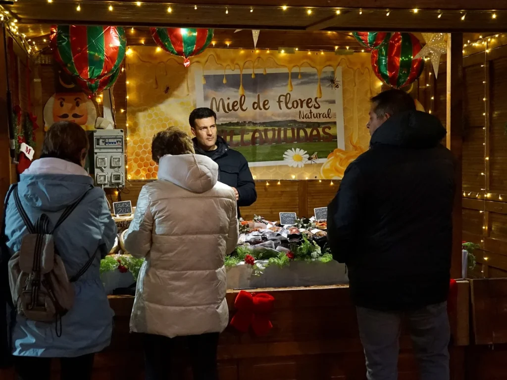 Visitantes comprando productos de alimentación en una caseta iluminada