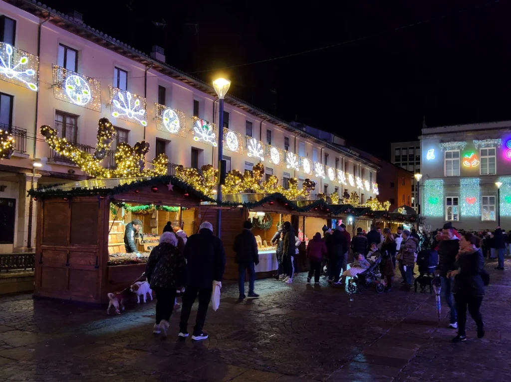 Casetas iluminadas y visitantes en la Plaza Mayor durante el Mercado Navideño de Palencia 2025
